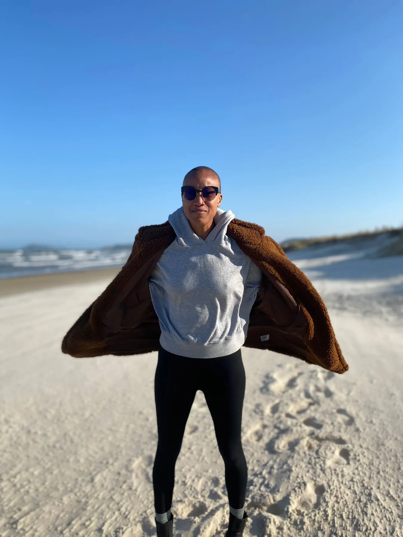 Diara standing confidently on a beach beneath an open blue sky