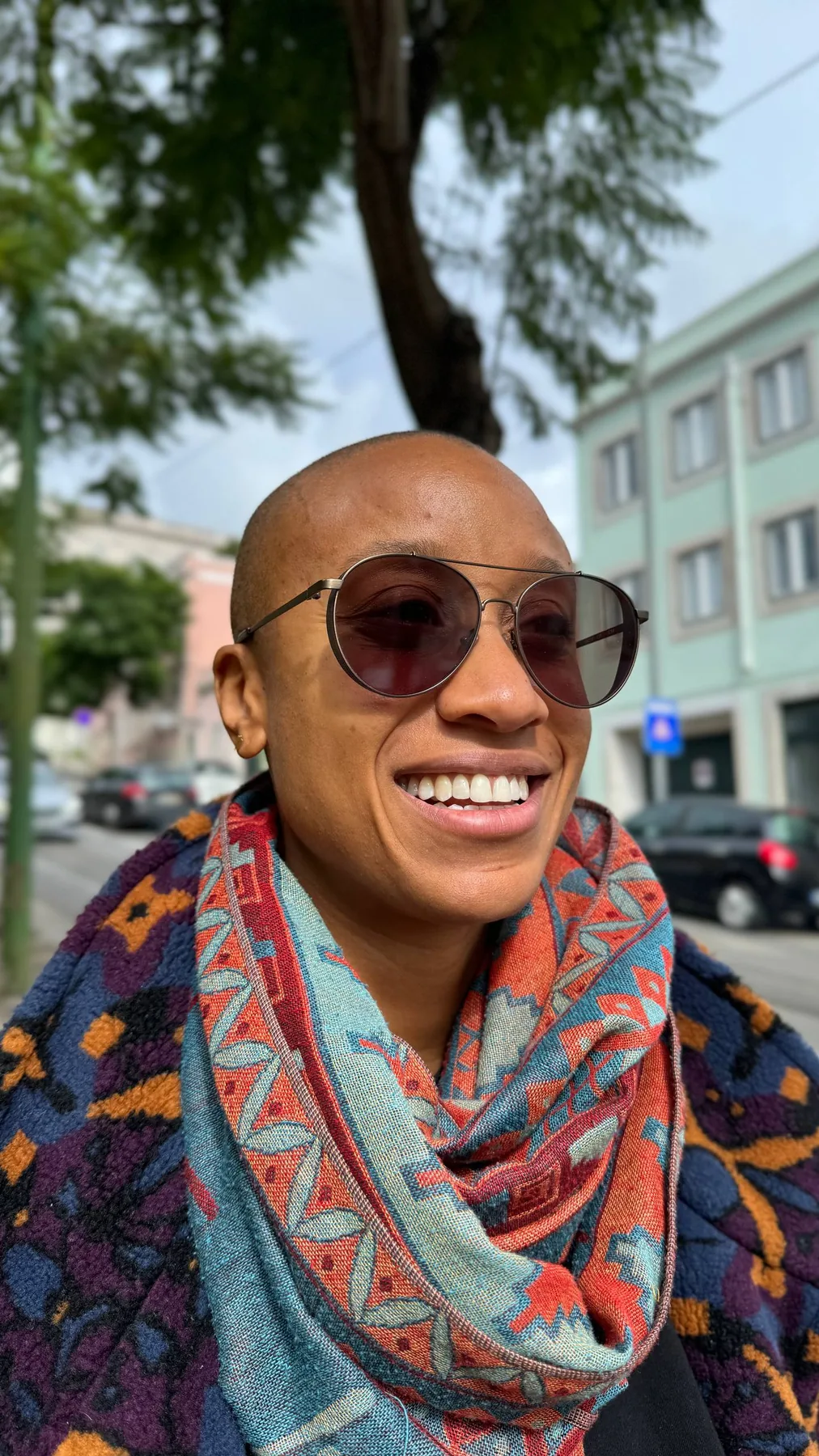 A joyful close portrait of Diara wearing sunglasses and a scarf