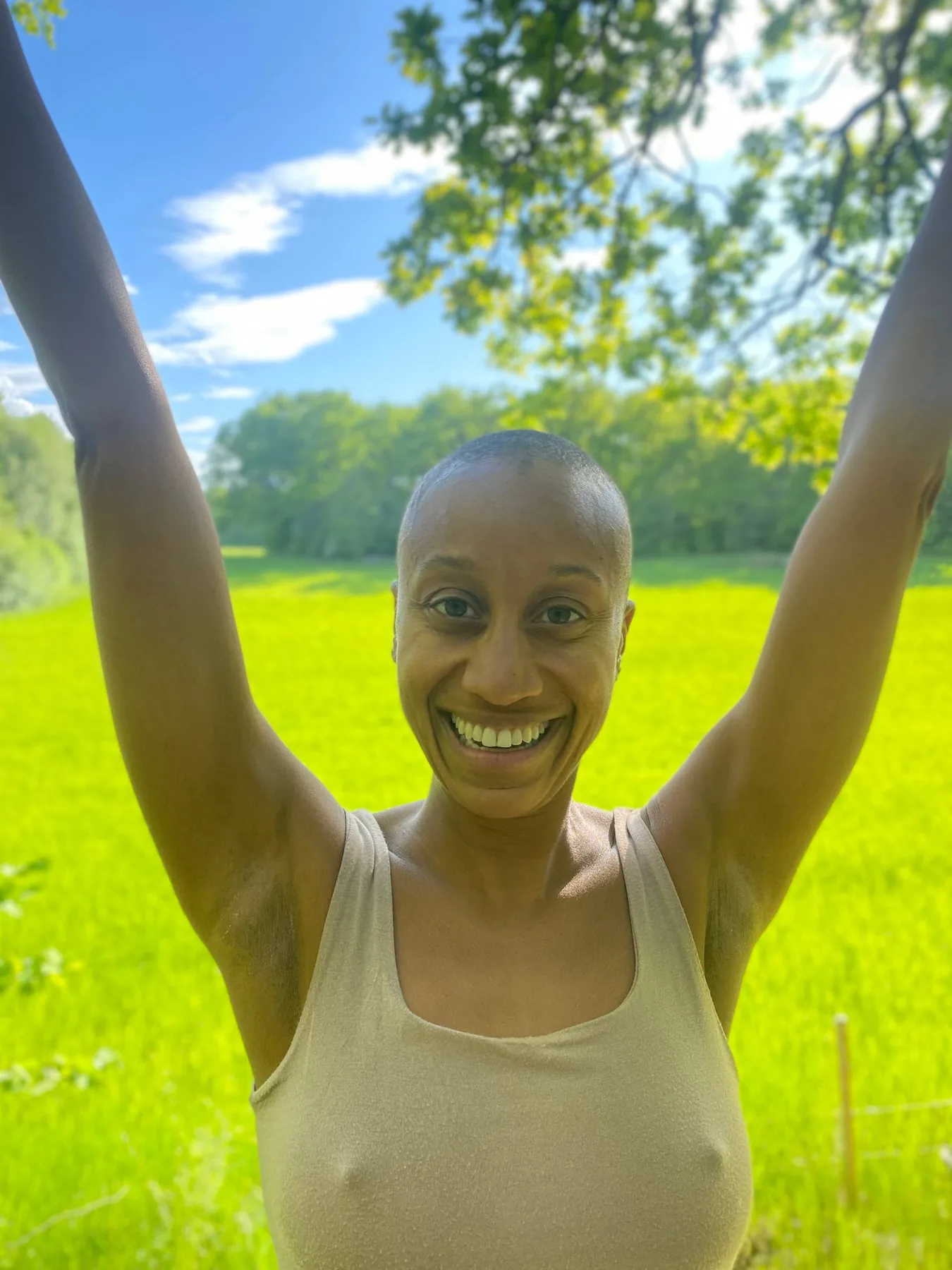 Diara standing in a green field with her arms raised